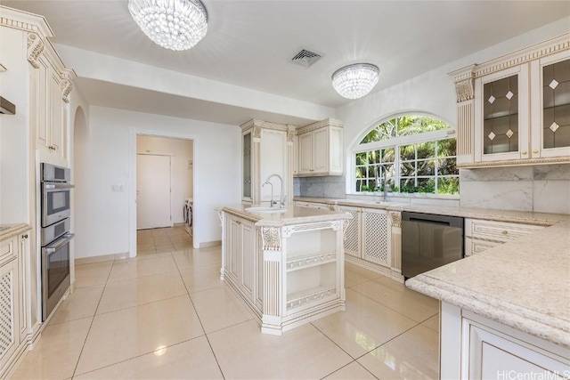 kitchen featuring a kitchen island, cream cabinets, appliances with stainless steel finishes, and a chandelier