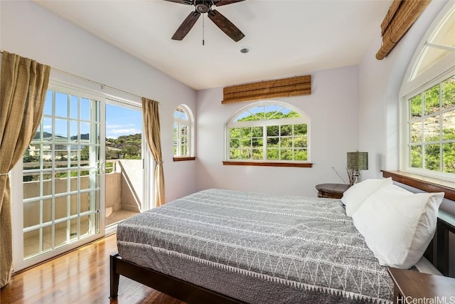 bedroom featuring multiple windows, hardwood / wood-style floors, ceiling fan, and access to exterior