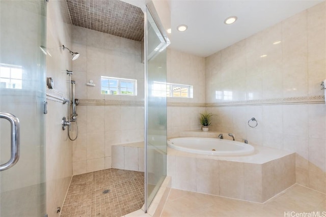 bathroom featuring tile patterned floors, independent shower and bath, and tile walls