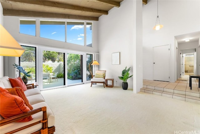 living area with beamed ceiling, a high ceiling, and light carpet