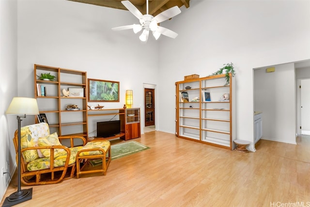 sitting room with a towering ceiling, light hardwood / wood-style floors, and ceiling fan