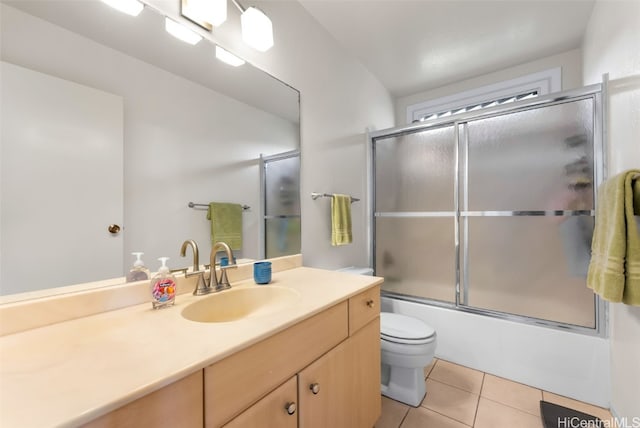 full bathroom with vanity, bath / shower combo with glass door, tile patterned floors, and toilet