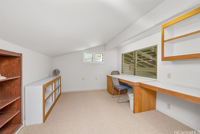 unfurnished office featuring lofted ceiling, built in desk, and light carpet