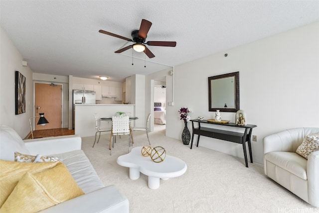 carpeted living room with ceiling fan and a textured ceiling