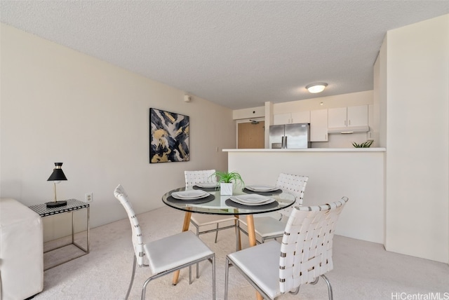 carpeted dining room with a textured ceiling