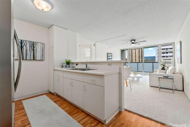 kitchen with sink, light hardwood / wood-style flooring, stainless steel refrigerator, a textured ceiling, and kitchen peninsula