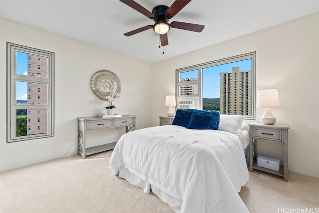 bedroom featuring ceiling fan, light carpet, and a textured ceiling