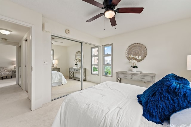 bedroom featuring light carpet, ceiling fan, and a closet