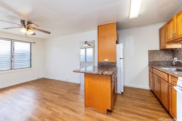 kitchen featuring sink, dark stone countertops, white refrigerator, kitchen peninsula, and light wood-type flooring