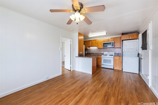 kitchen with stacked washer and clothes dryer, dark hardwood / wood-style floors, white appliances, and decorative backsplash