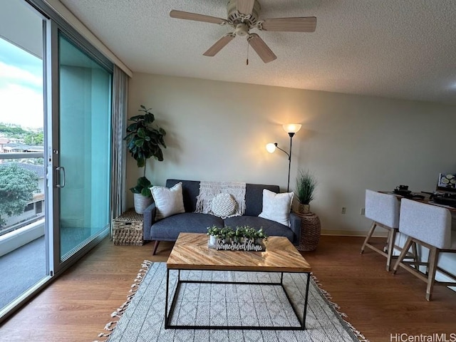 living room featuring ceiling fan, wood-type flooring, and a textured ceiling