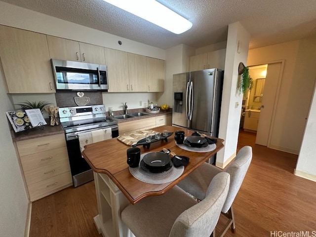 kitchen with sink, light wood-type flooring, a textured ceiling, and appliances with stainless steel finishes