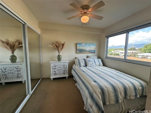 carpeted bedroom featuring ceiling fan, a closet, and a textured ceiling