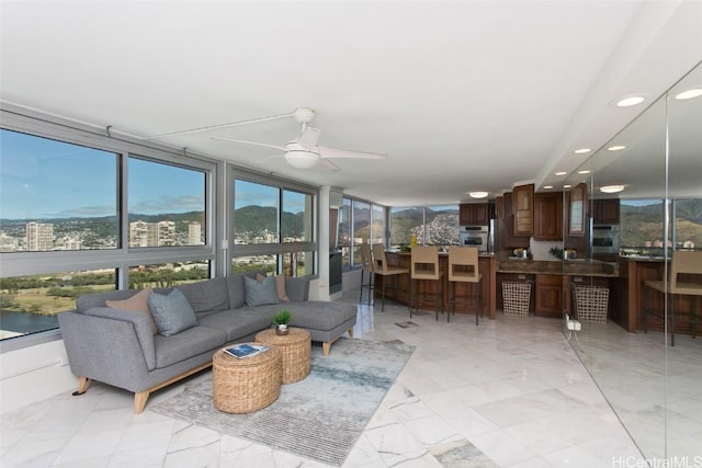 living room with ceiling fan, a wall of windows, and a wealth of natural light