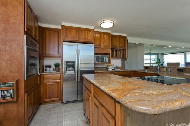 kitchen featuring light stone counters, stainless steel appliances, and sink