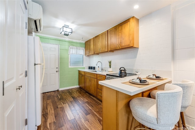 kitchen featuring a breakfast bar, dark hardwood / wood-style floors, sink, white refrigerator, and kitchen peninsula