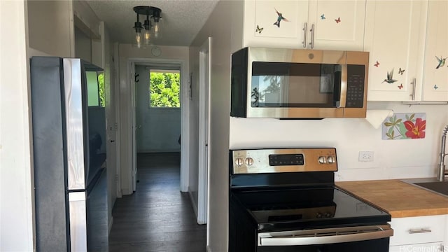 kitchen with stainless steel appliances, dark wood-type flooring, white cabinets, and a textured ceiling