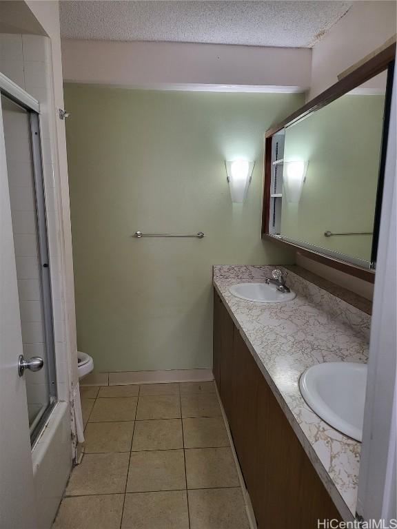 full bathroom with toilet, a textured ceiling, vanity, enclosed tub / shower combo, and tile patterned flooring