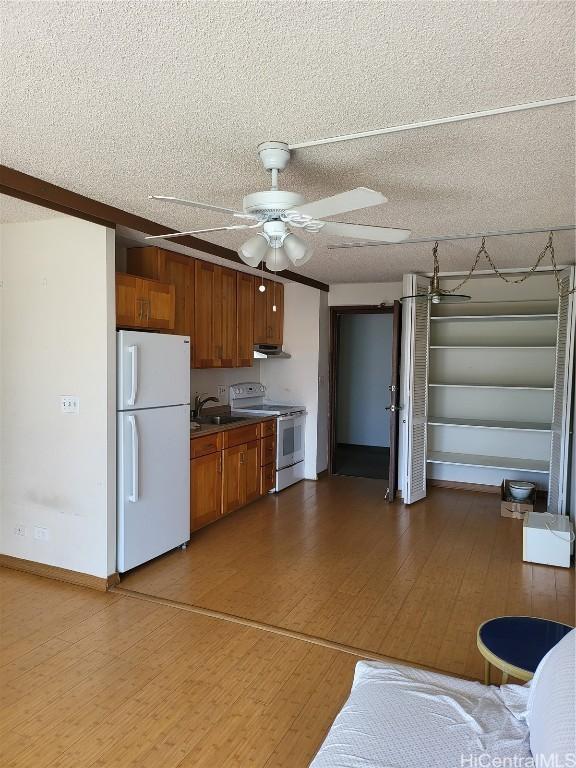 kitchen featuring sink, white appliances, ceiling fan, hardwood / wood-style floors, and a textured ceiling