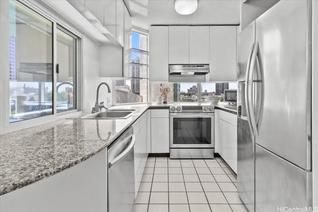 kitchen featuring sink, white cabinets, light tile patterned floors, light stone counters, and stainless steel appliances