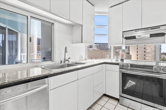 kitchen with sink, a textured ceiling, light tile patterned floors, stainless steel appliances, and white cabinets