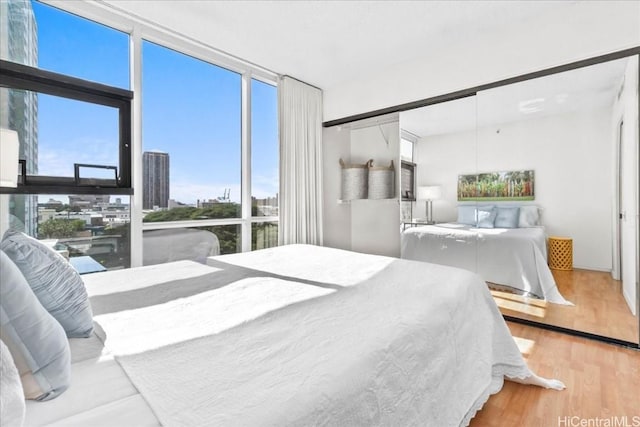 bedroom with floor to ceiling windows and light hardwood / wood-style floors