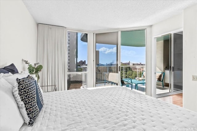 bedroom featuring a textured ceiling, hardwood / wood-style floors, access to exterior, and a wall of windows