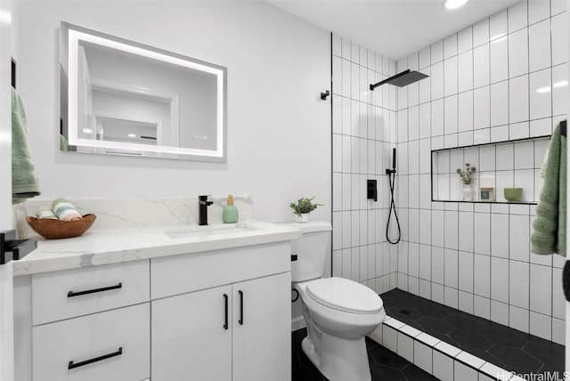 bathroom featuring vanity, toilet, and a tile shower