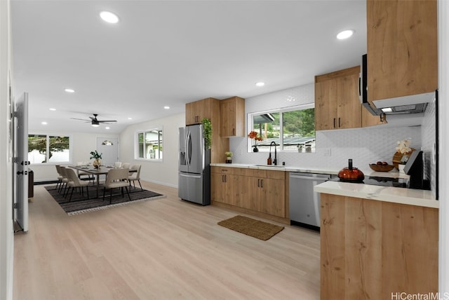 kitchen featuring sink, light hardwood / wood-style flooring, ceiling fan, appliances with stainless steel finishes, and tasteful backsplash