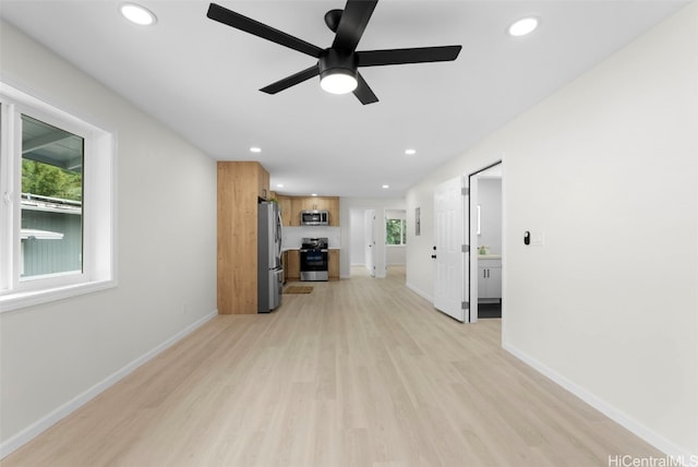 unfurnished living room featuring ceiling fan, plenty of natural light, and light wood-type flooring