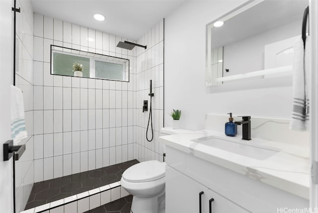 bathroom with vanity, tiled shower, and toilet