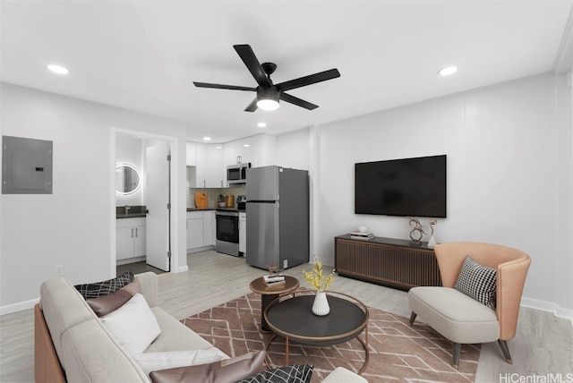 living room with ceiling fan, sink, electric panel, and light wood-type flooring