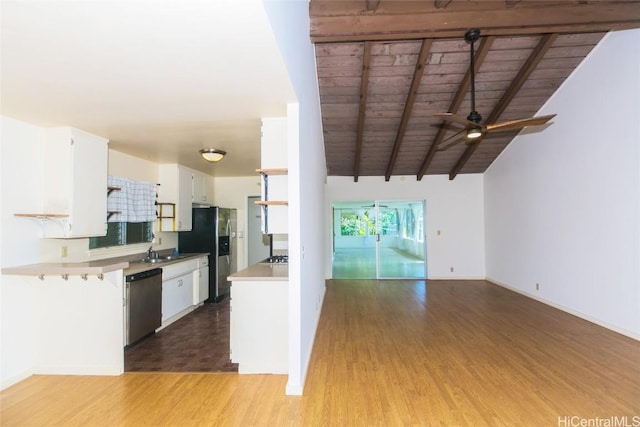 kitchen with stainless steel appliances, sink, lofted ceiling with beams, and white cabinets