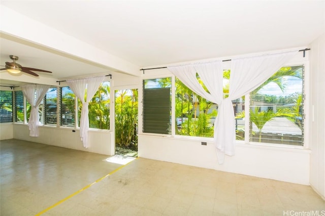 unfurnished sunroom featuring a healthy amount of sunlight and ceiling fan