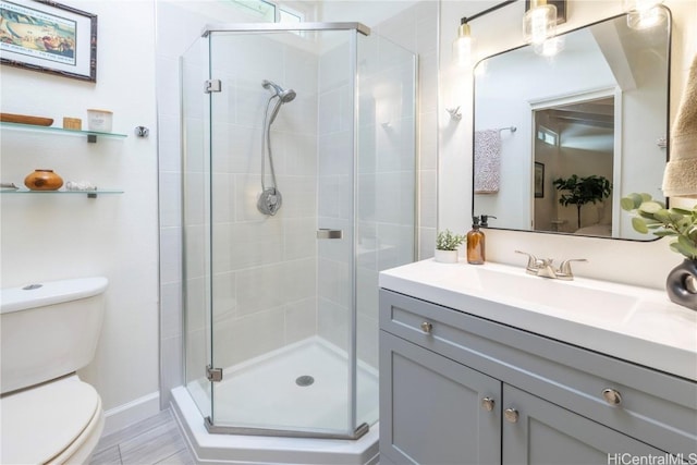 bathroom with vanity, a shower with door, and toilet