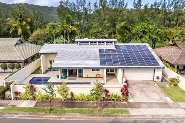 view of front of home with a mountain view, a garage, and solar panels