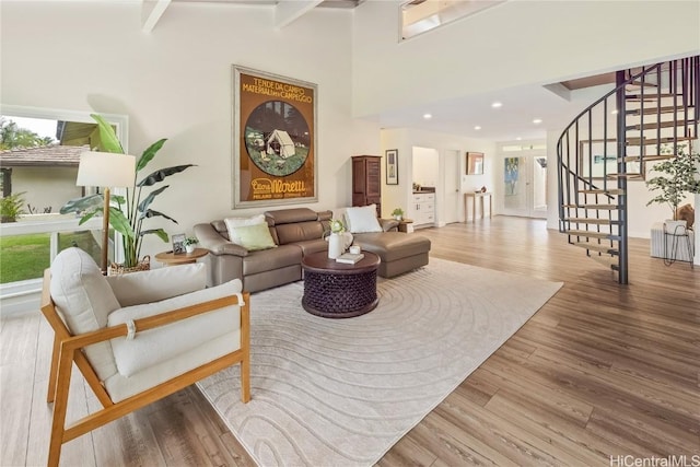 living room with beam ceiling, a towering ceiling, and wood-type flooring