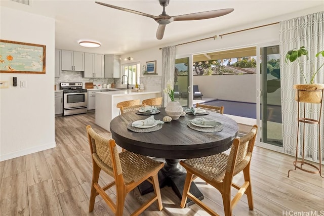 dining room with sink, light hardwood / wood-style floors, and ceiling fan