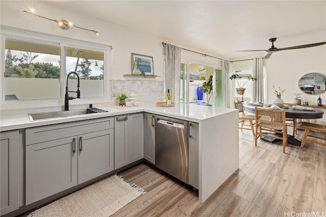 kitchen with stainless steel dishwasher, a healthy amount of sunlight, kitchen peninsula, and sink