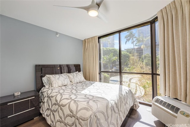 bedroom with expansive windows, dark hardwood / wood-style floors, a wall mounted AC, and ceiling fan