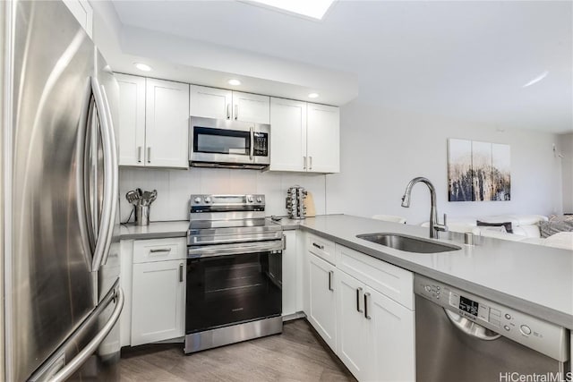 kitchen featuring white cabinetry, appliances with stainless steel finishes, sink, and kitchen peninsula