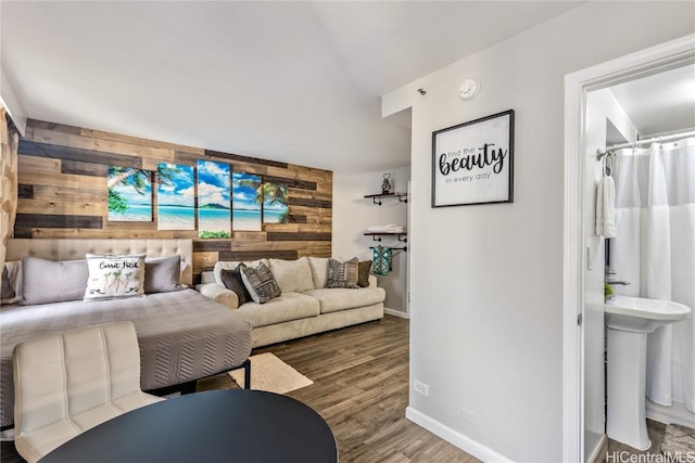 living room with sink, hardwood / wood-style floors, and wood walls