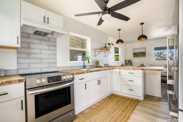 kitchen with wood counters, hanging light fixtures, white cabinetry, and stainless steel range with electric cooktop