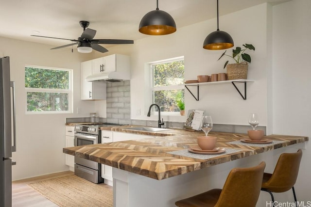 kitchen featuring white cabinetry, decorative light fixtures, wood counters, and a kitchen breakfast bar