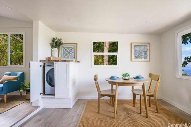 dining area with washer / clothes dryer and light wood-type flooring