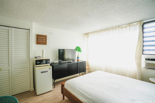 bedroom with a closet, a textured ceiling, and light hardwood / wood-style flooring