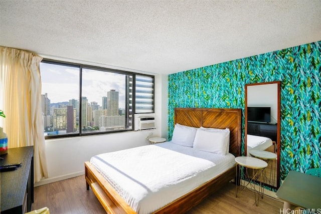 bedroom featuring hardwood / wood-style flooring, a textured ceiling, and cooling unit