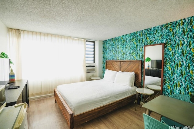 bedroom with cooling unit, wood-type flooring, and a textured ceiling