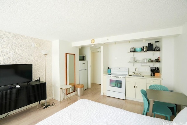 bedroom with white refrigerator, sink, a textured ceiling, and light hardwood / wood-style floors