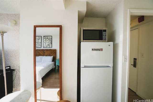 kitchen featuring hardwood / wood-style flooring, a textured ceiling, and white fridge